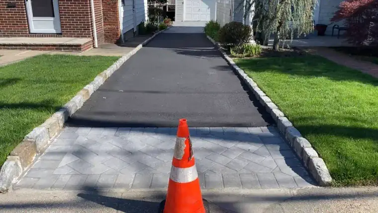 New asphalt driveway with a safety cone at the entrance