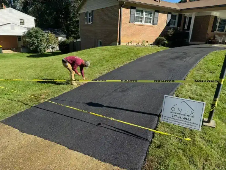 Freshly paved asphalt driveway curving toward a residential street