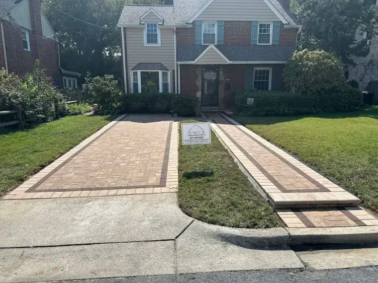 Paver driveway with a contrasting border band leading to a brick colonial