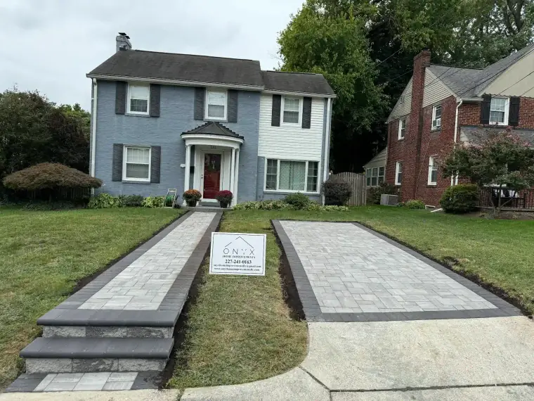 Paver driveway and walkway in front of a blue two-story home