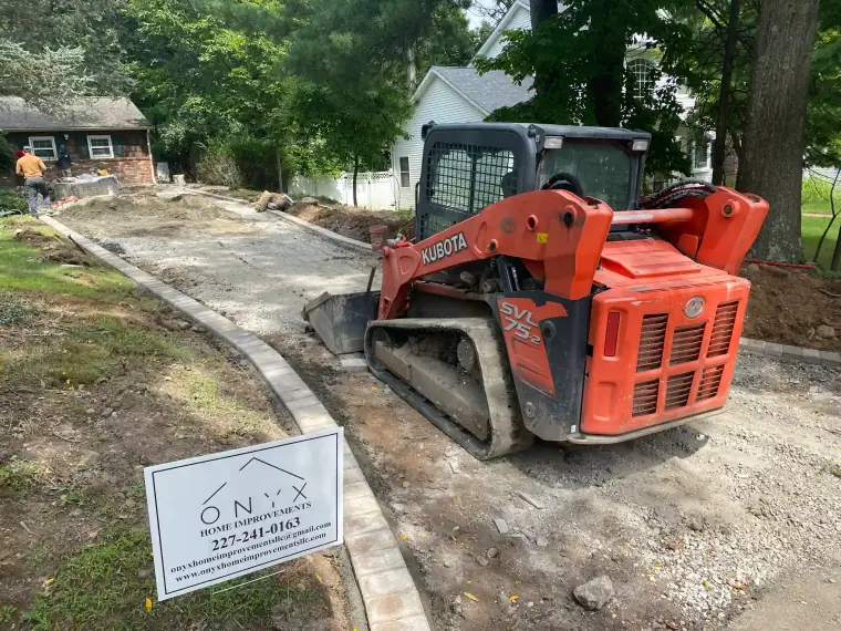 Skid steer tearing out an old driveway in preparation for new asphalt
