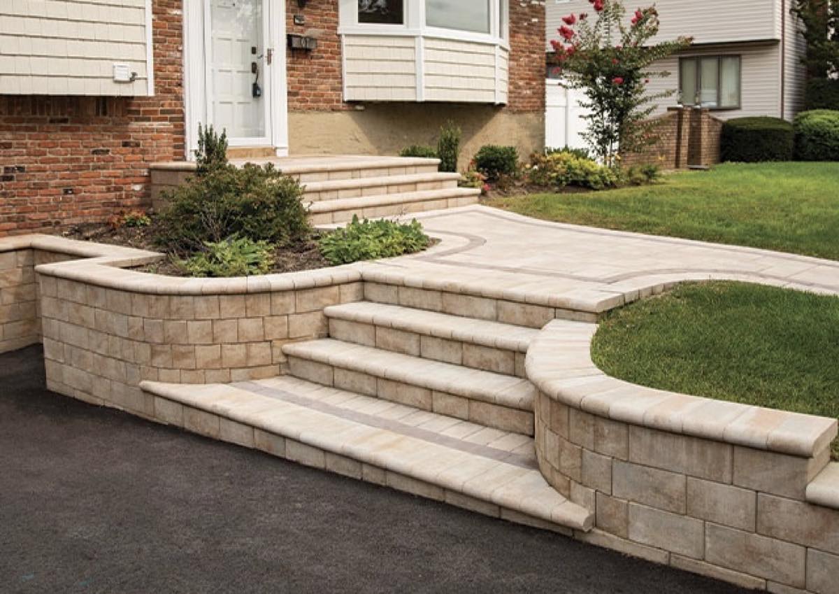 Curved cream segmental block retaining wall with integrated steps and a paver landing at the front entrance of a Vienna home