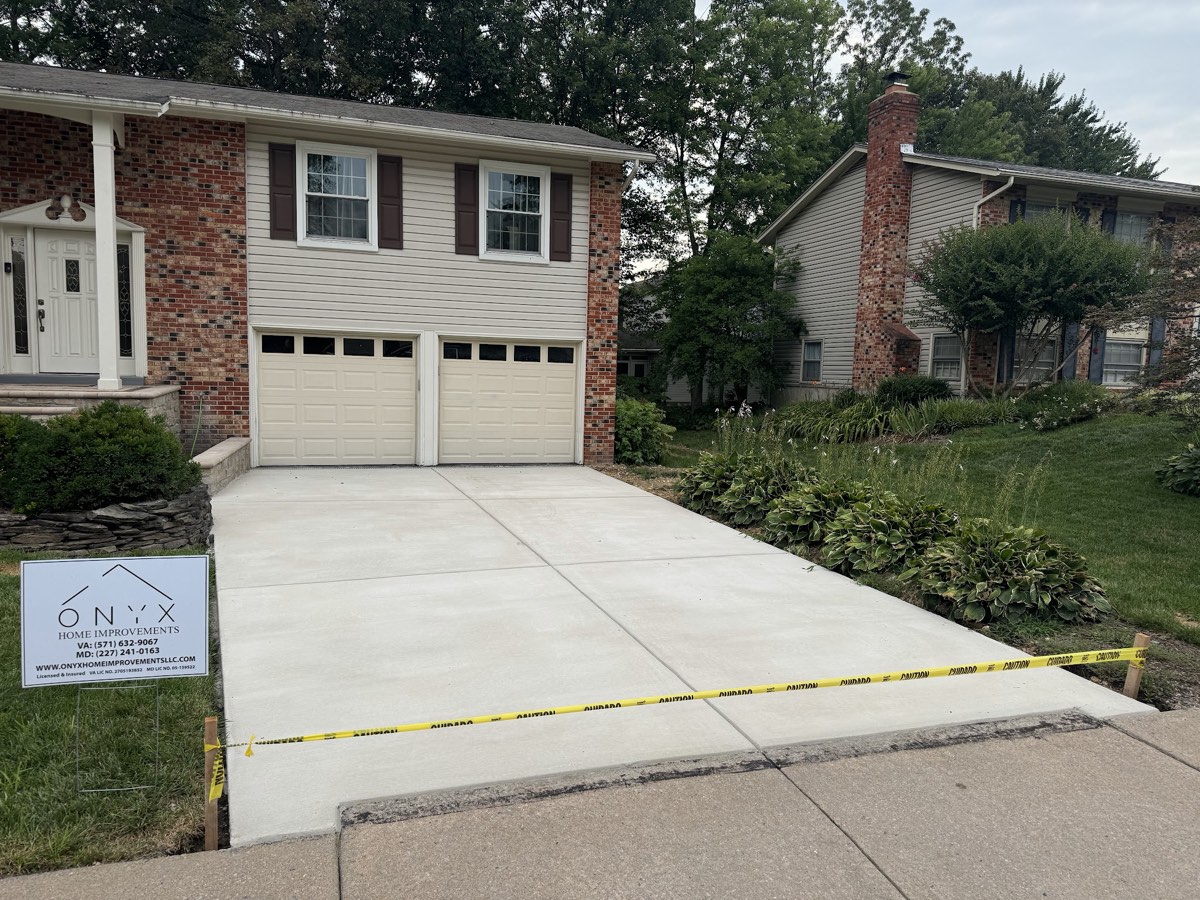 Freshly poured broom-finished concrete driveway running to a two-car garage, taped off while it cures