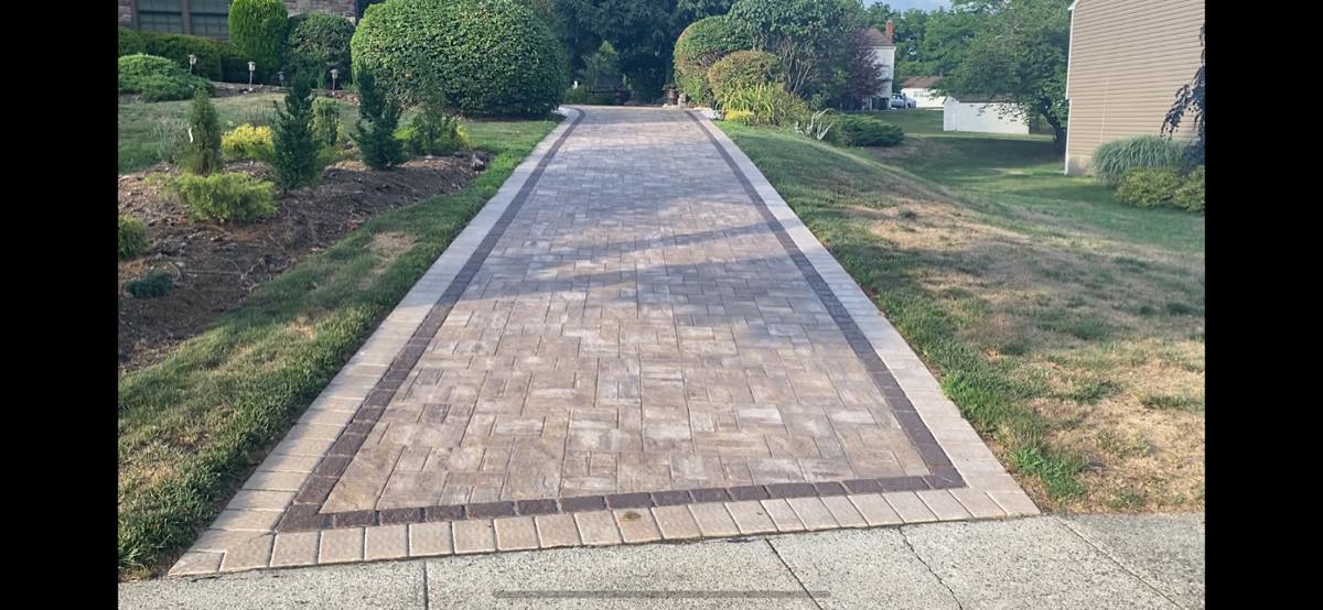 Wide paver walkway with a contrasting soldier-course border running from the public sidewalk toward a Fairfax home