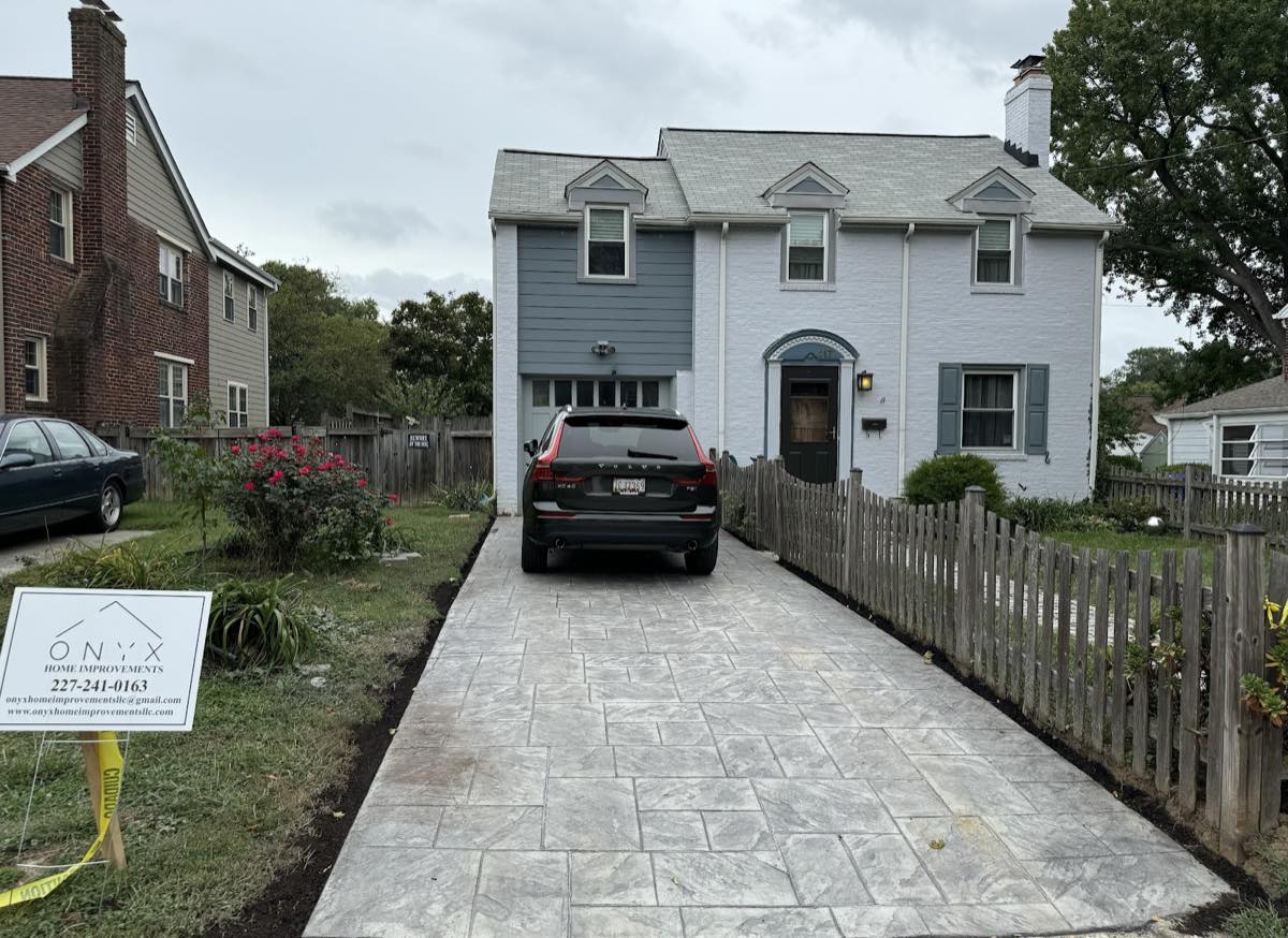 Stamped concrete driveway in a large-format ashlar slate pattern running to the garage of a white Annandale colonial