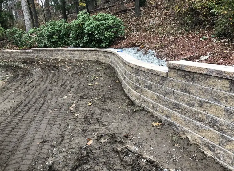 Natural stone retaining wall under construction on a sloped yard