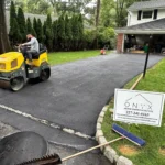 Onyx Home Improvement LLC contractor on top of a steam roller going over freshly laid asphalt.