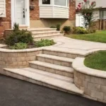 Stone retaining wall and steps surrounded by small patches of grass.