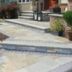 Beautiful stone work of three elongated steps that lead up to the front door of a residential home.