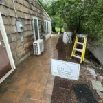 Brick flooring surrounded by a home and trees.