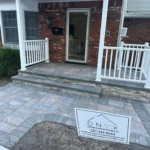 Beautiful stone work of two steps that lead up to the front door of a residential home.