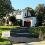 Beautiful two story home with red brick chimney on the side. Trees surround the home.