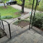 Natural stone staircase and green grass filled yard and bushes.