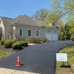 Residential home with new asphalt driveway. A lush front yard with green grass and bushes.