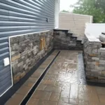 Stainless steel BBQ pit enclosed by retaining walls.