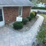 Stone walkway wrapping around a residential home and its garden.