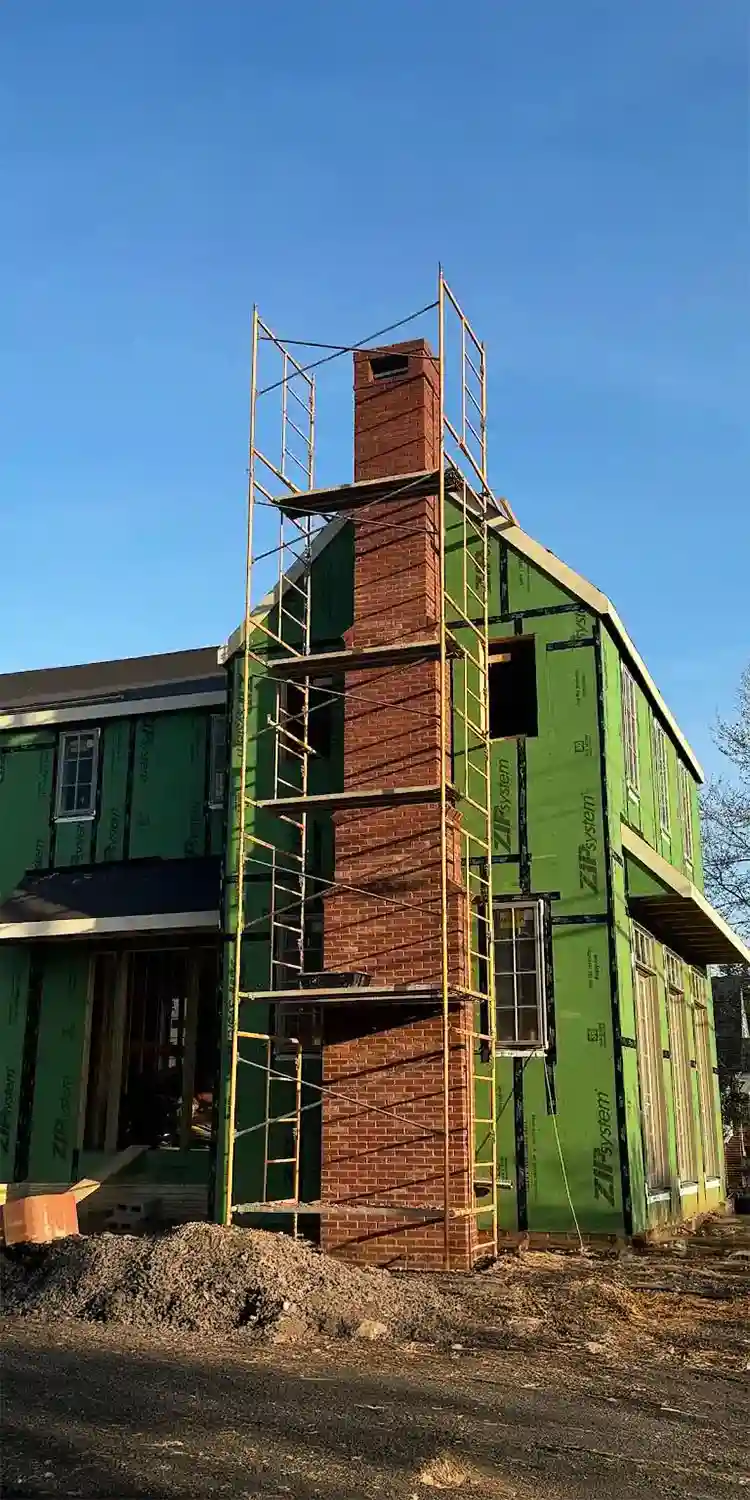 Tall chimney newly installed in a two story house under construction.