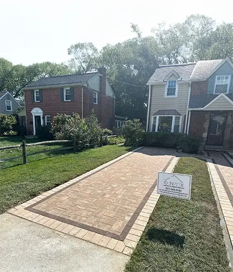 Front view of a stone driveway surrounded by two story homes and small front yards with patches of grass.