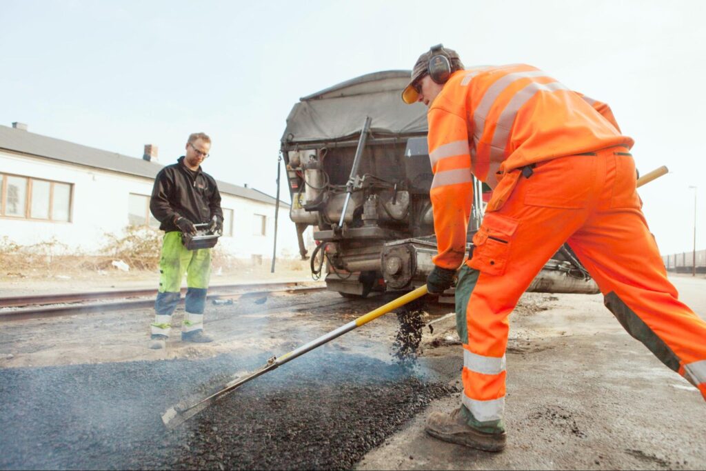 Workers manually paving a driveway with asphalt.