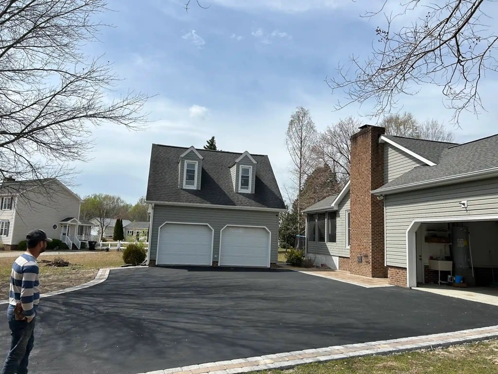 Modern home with clean driveway paving in front of twin garage doors.