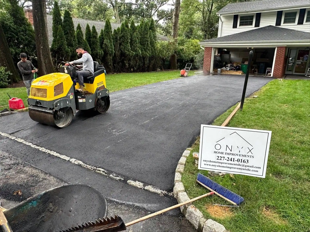 Concrete driveway paving is underway, with workers leveling the surface.