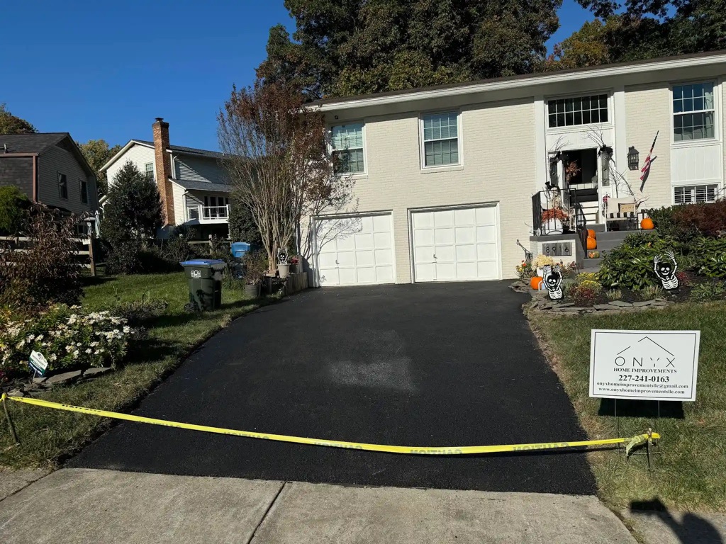 New black asphalt surface curing after driveway paving work.