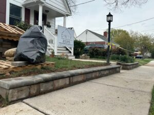 House facade with freshly restored and sealed foundation base; a black trash bag sits in the foreground.
