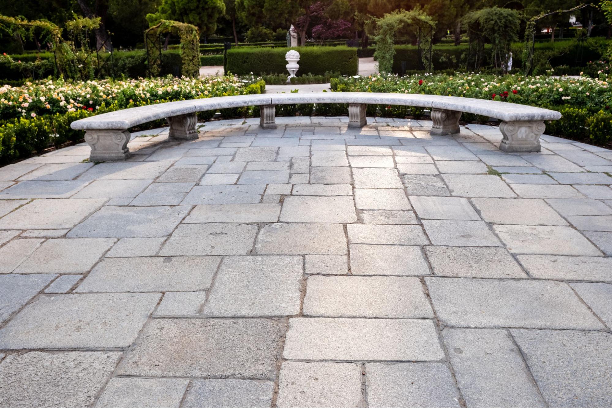 A stone patio overlooking a large garden at an estate.