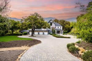 A newly-built home with an expansive driveway at sunset.