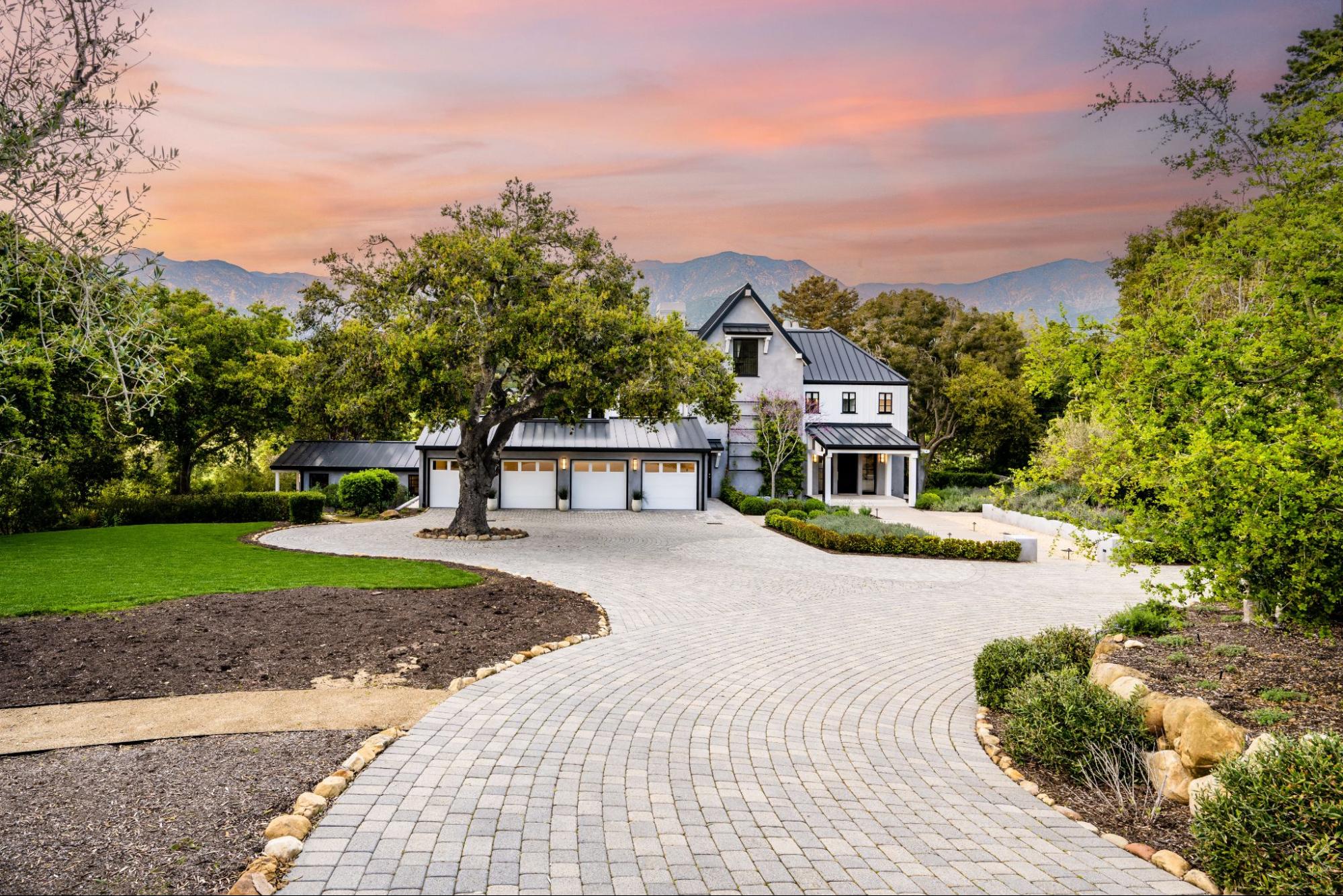 A newly-built home with an expansive driveway at sunset.