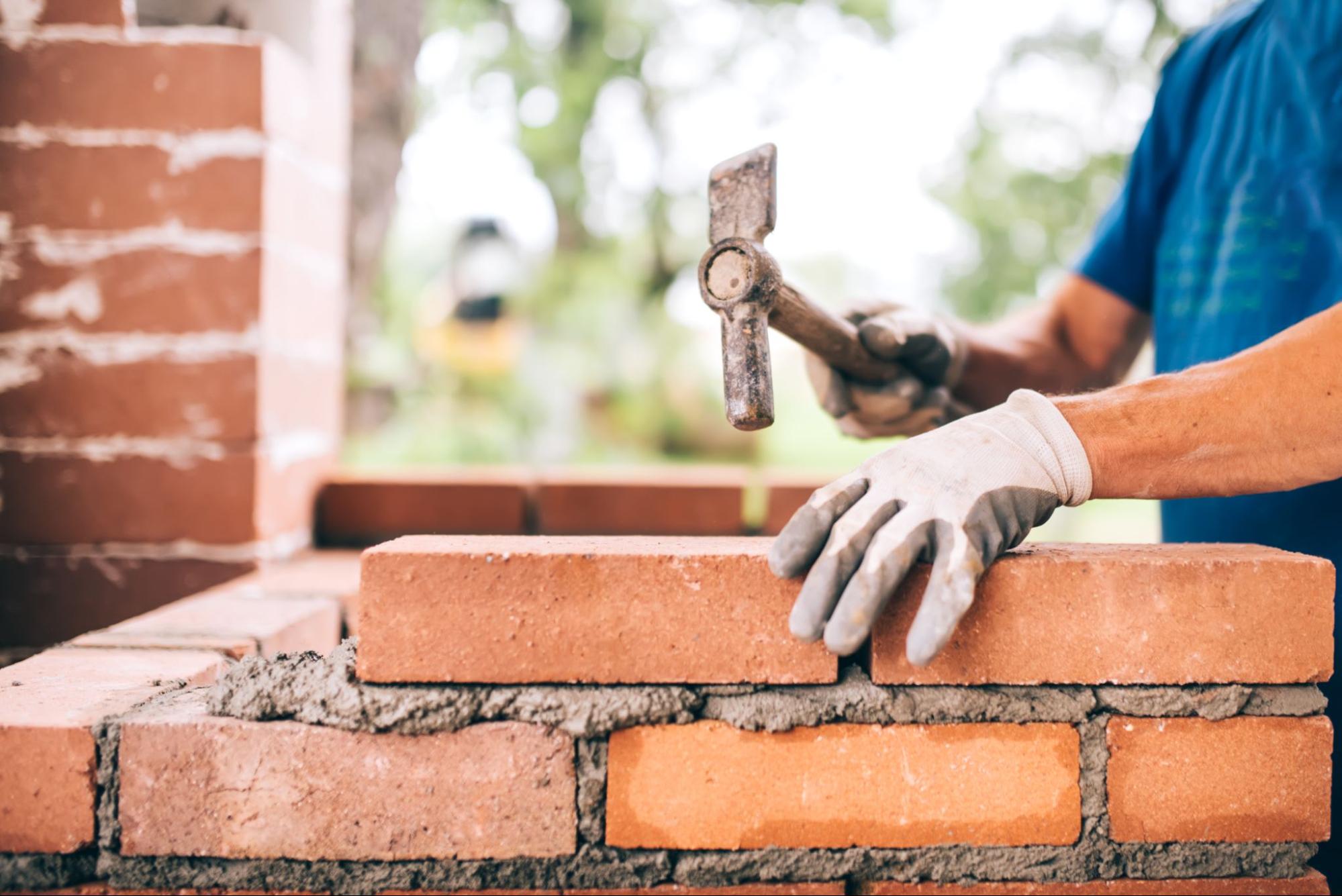 An industrial worker is laying bricks.