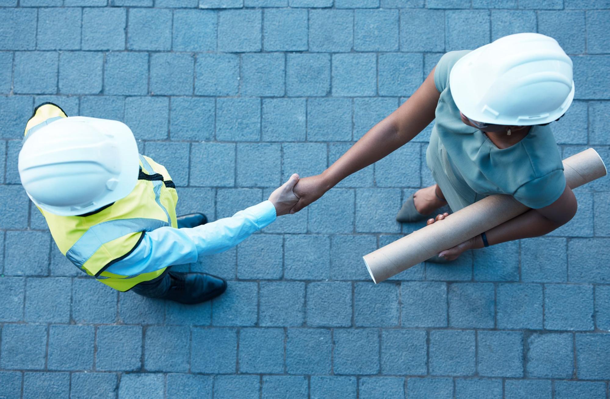 Top-down view of a client handshake with a contractor during a meeting at a property construction site