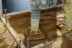 A professional uses a compaction tool to set a solid foundation.
