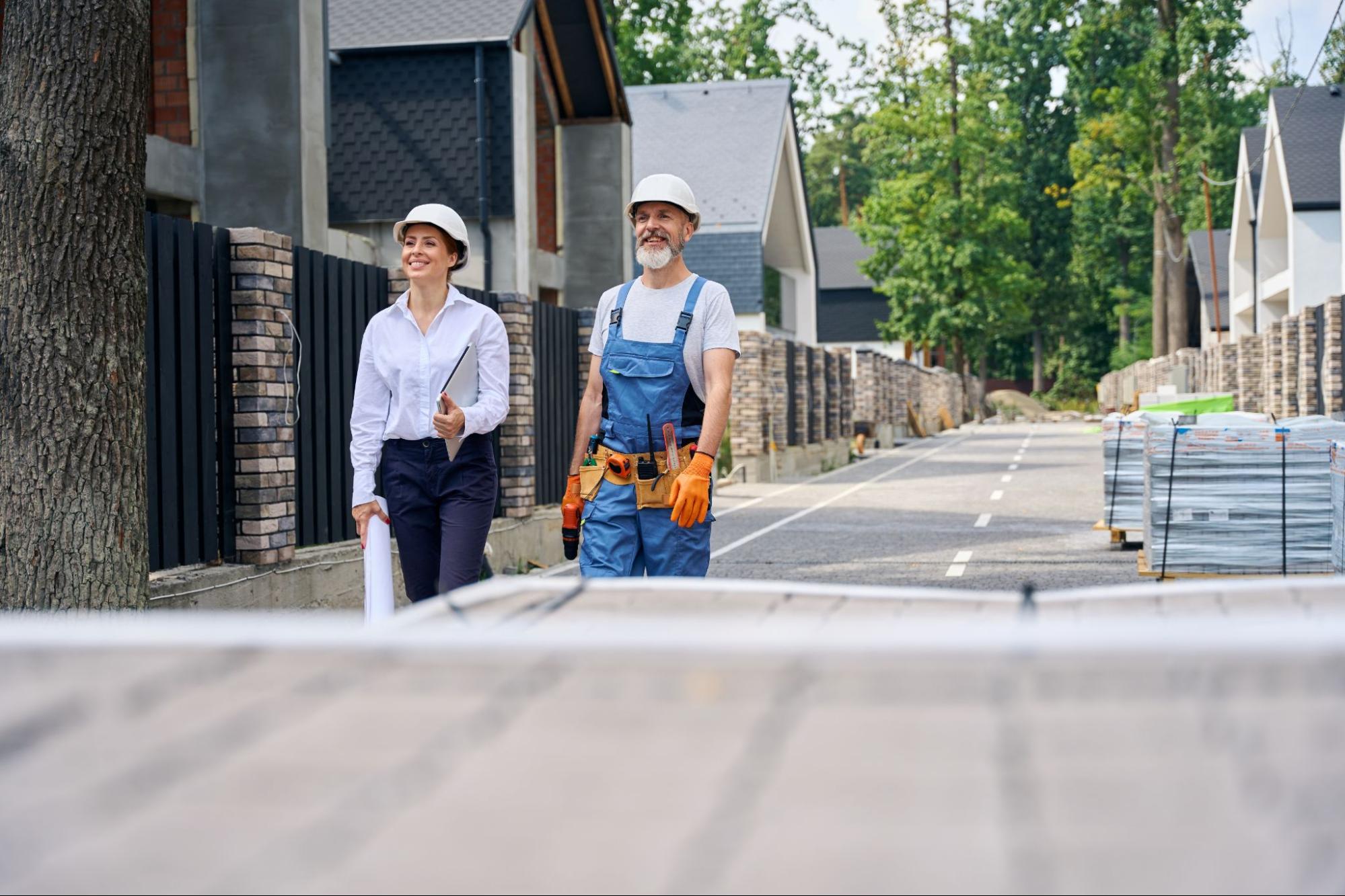 A homeowner and paving contractor walk the newly paved driveway together, examining the quality and alignment