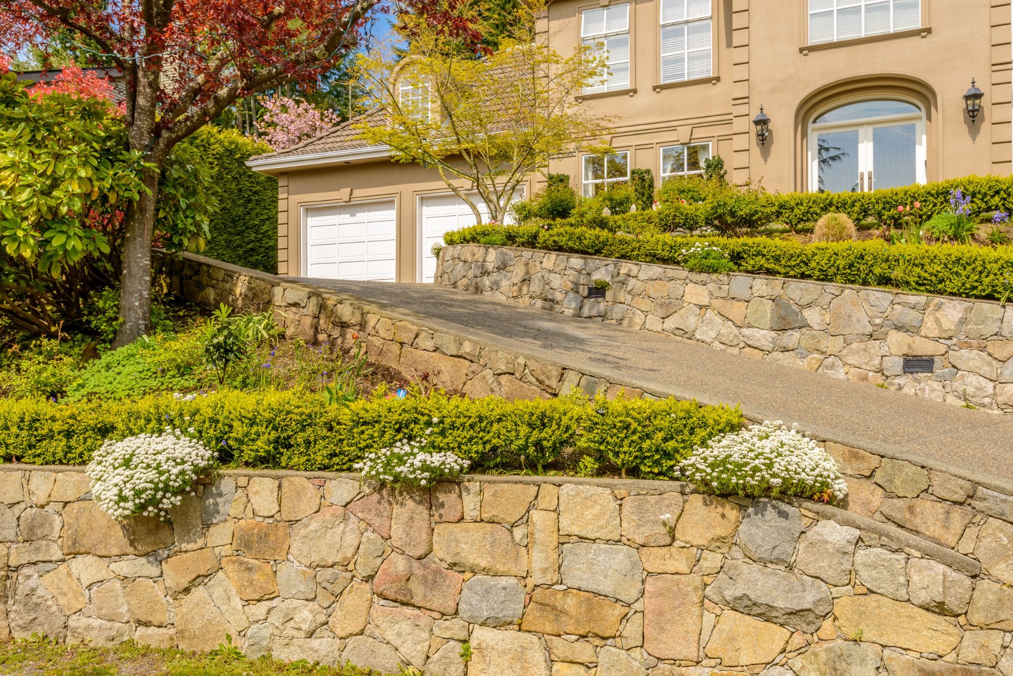 Retaining wall beside a residential driveway with a home in the background.
