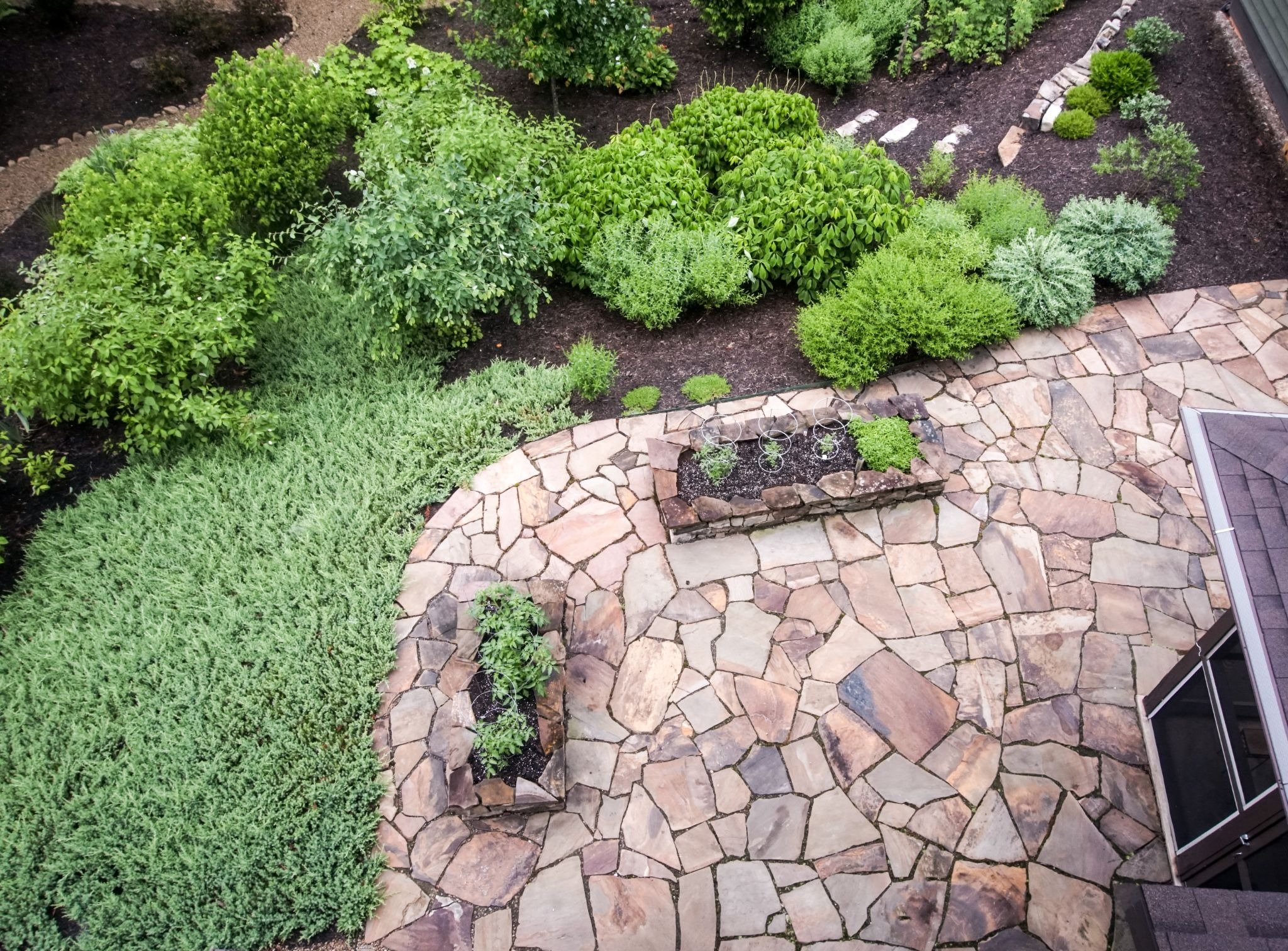 Overhead view of a patio made of stone with grass and plants.