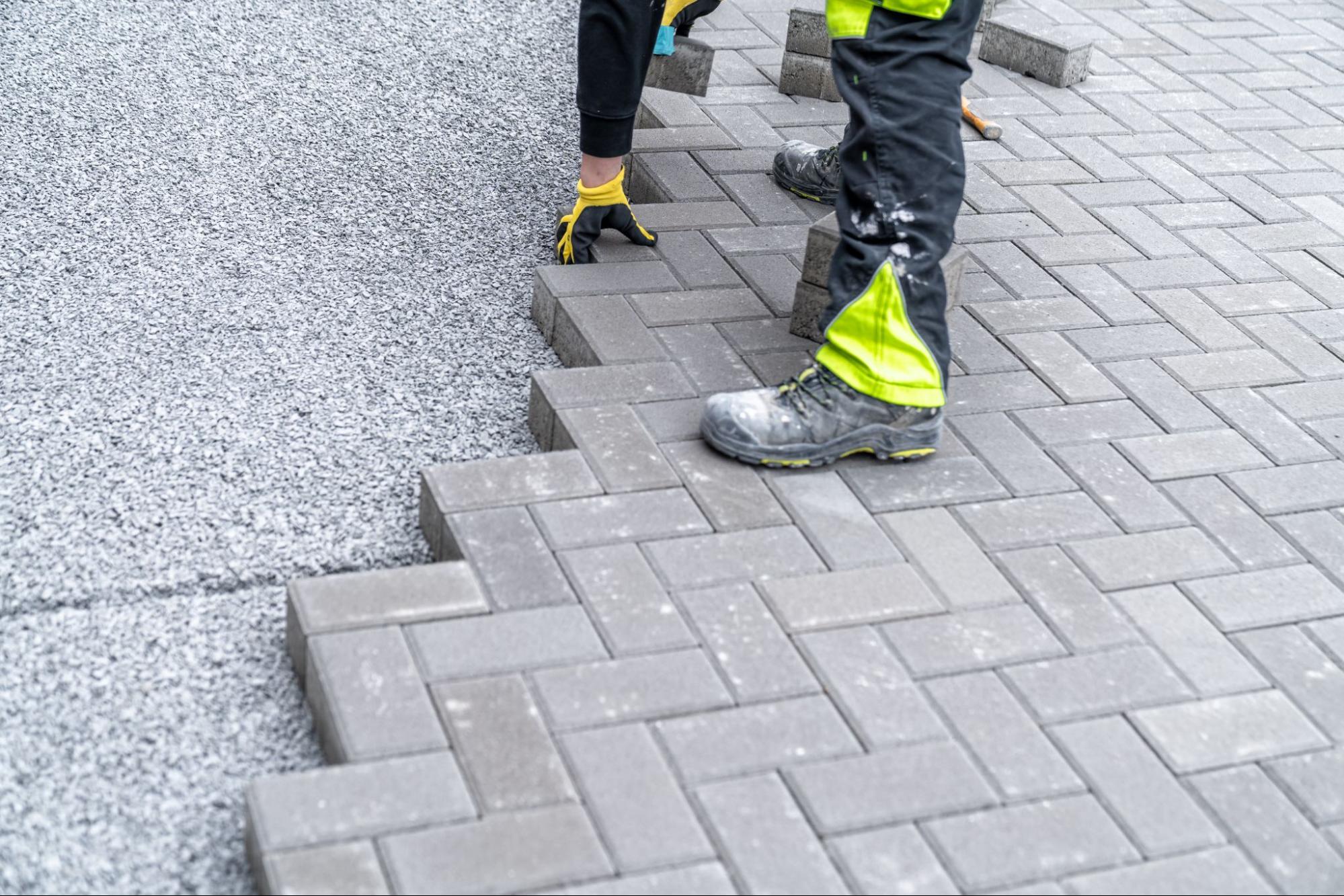 Paving contractor installing stone pavers.