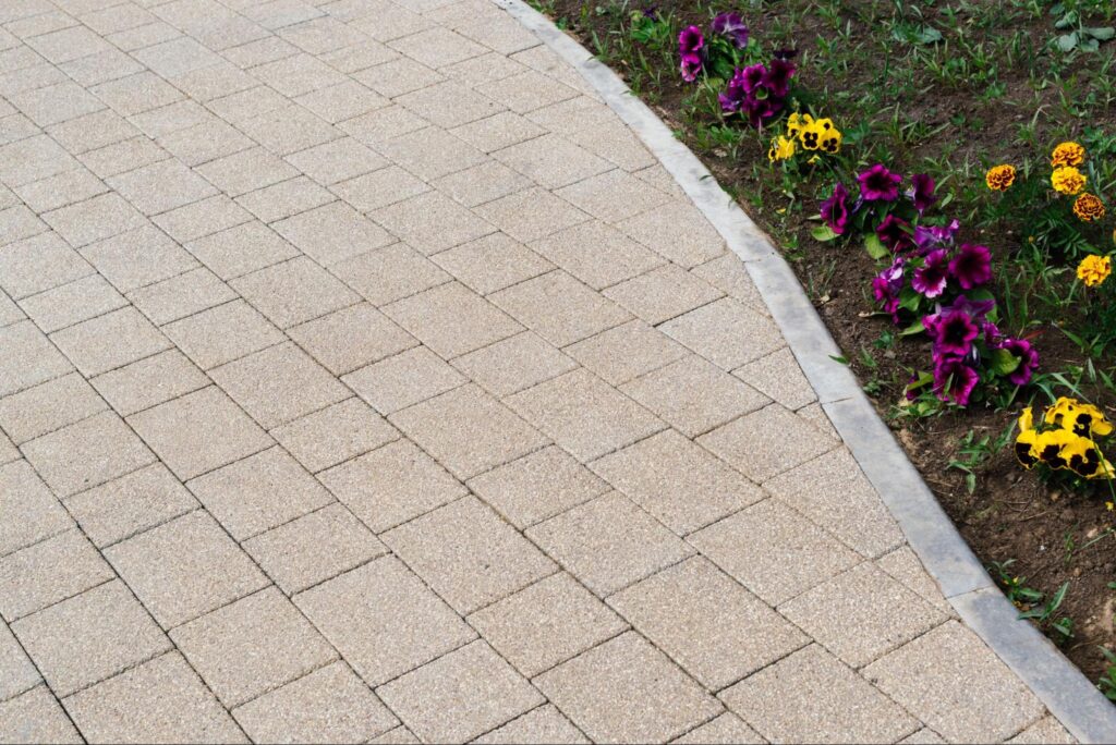 Brick paver driveway with a border next to a flower bed.