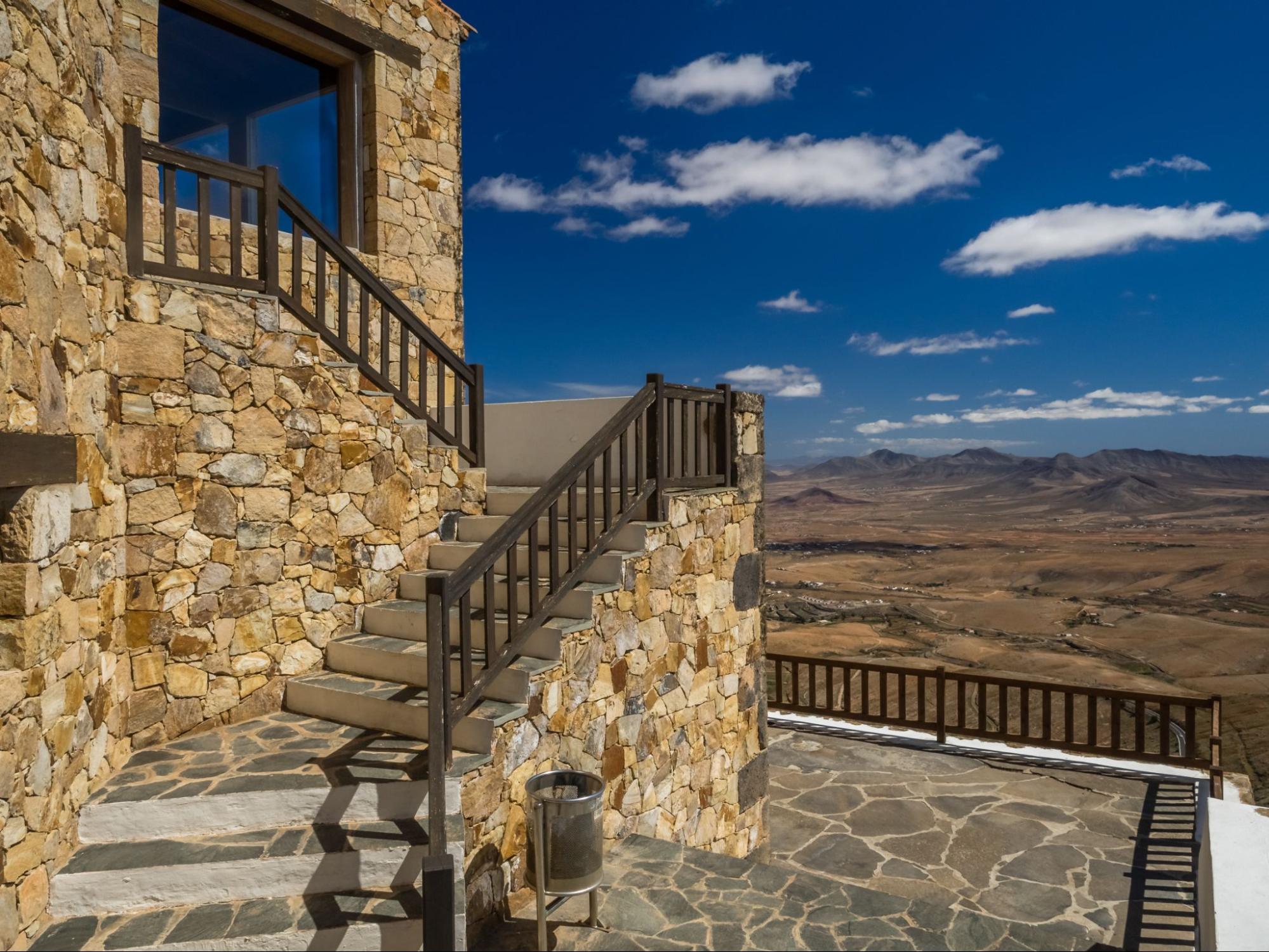 Stone stairs leading up to a home with mountains in the background.