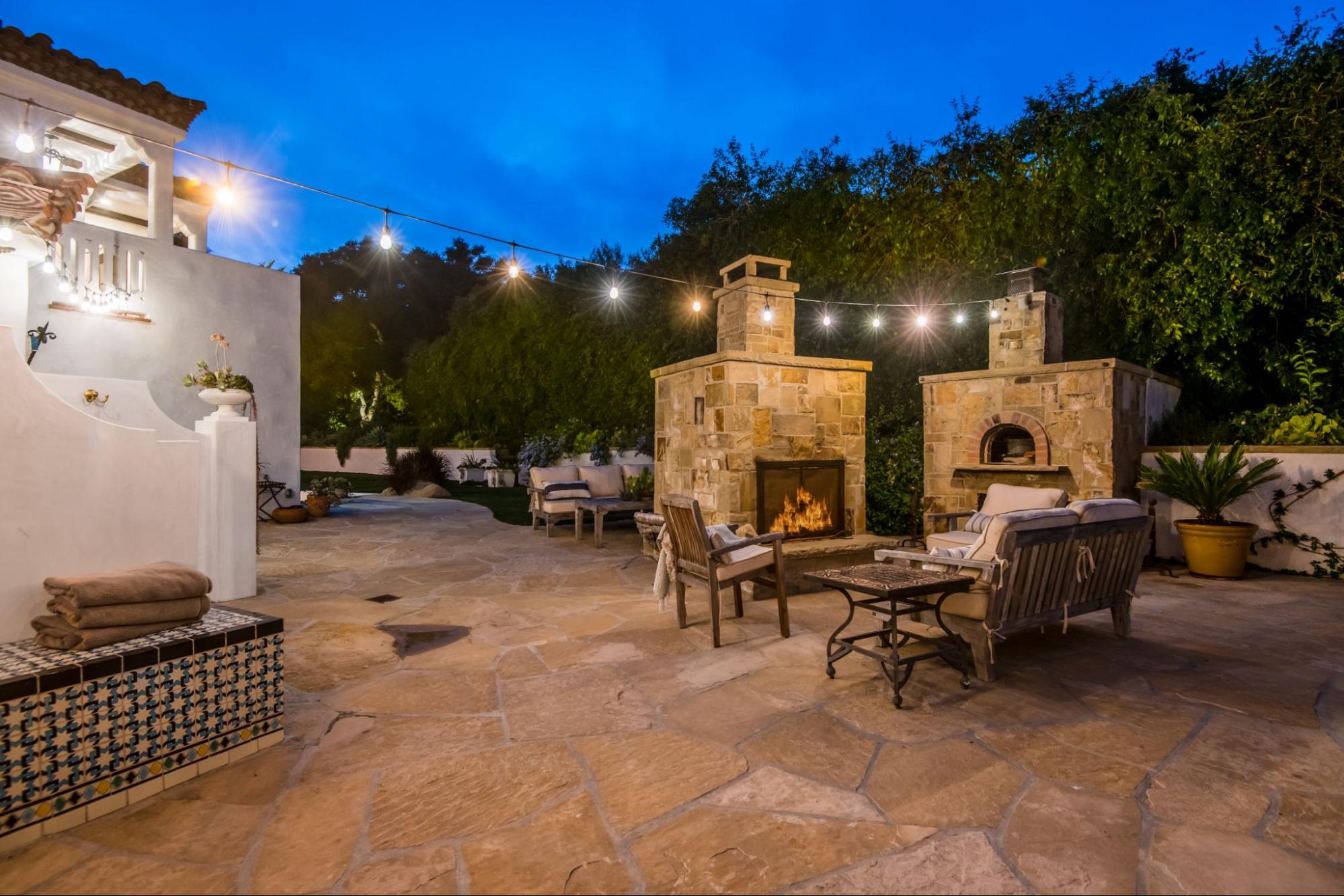 Luxury villa patio with two outdoor fireplaces, elegant seating, and a spacious, high-end outdoor living area